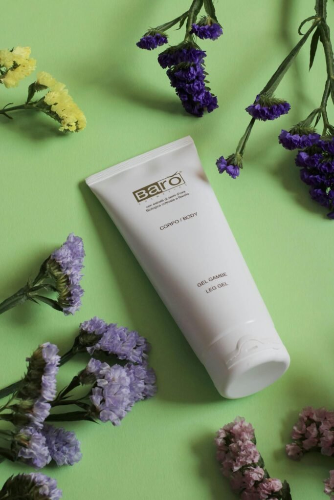 Cosmetic product tube with flowers on a green backdrop, perfect for skincare promotions.